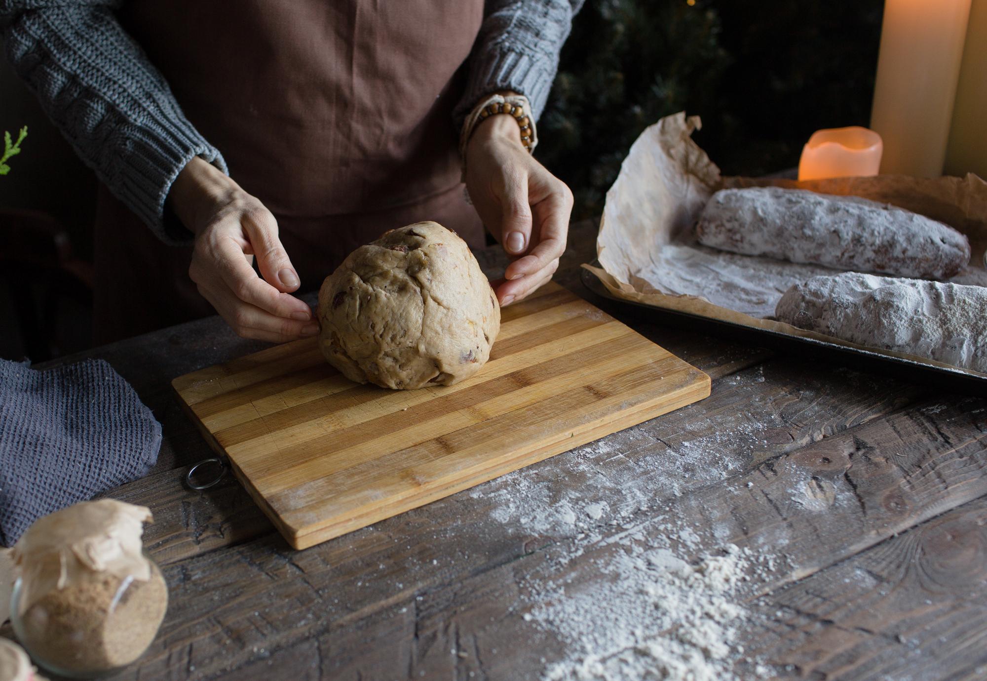 Hands shaping dough on wooden board
