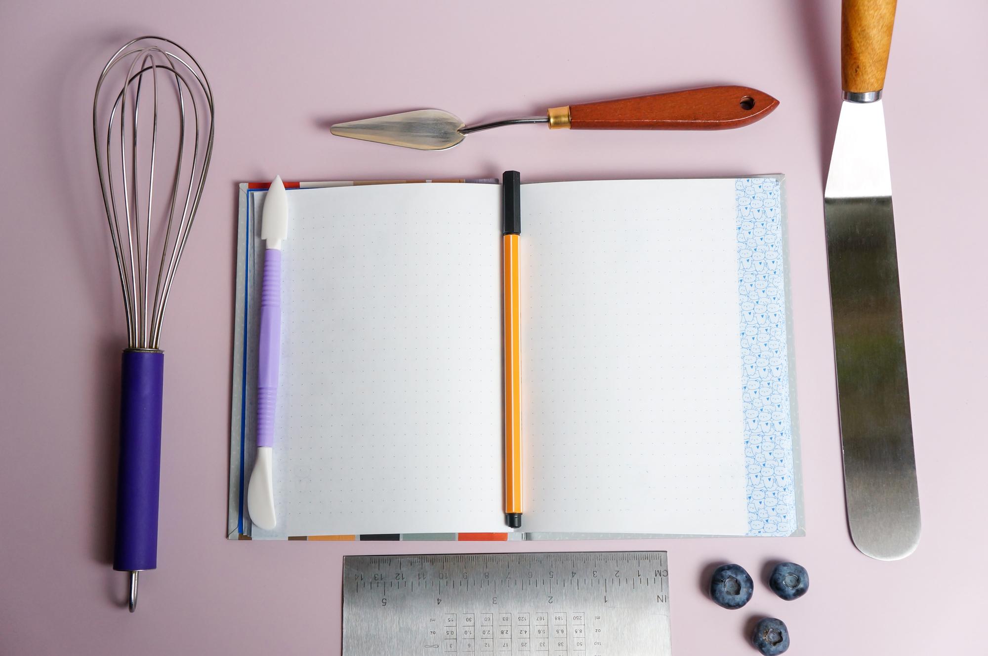 Set of cookbook and kitchen tools on pastel surface